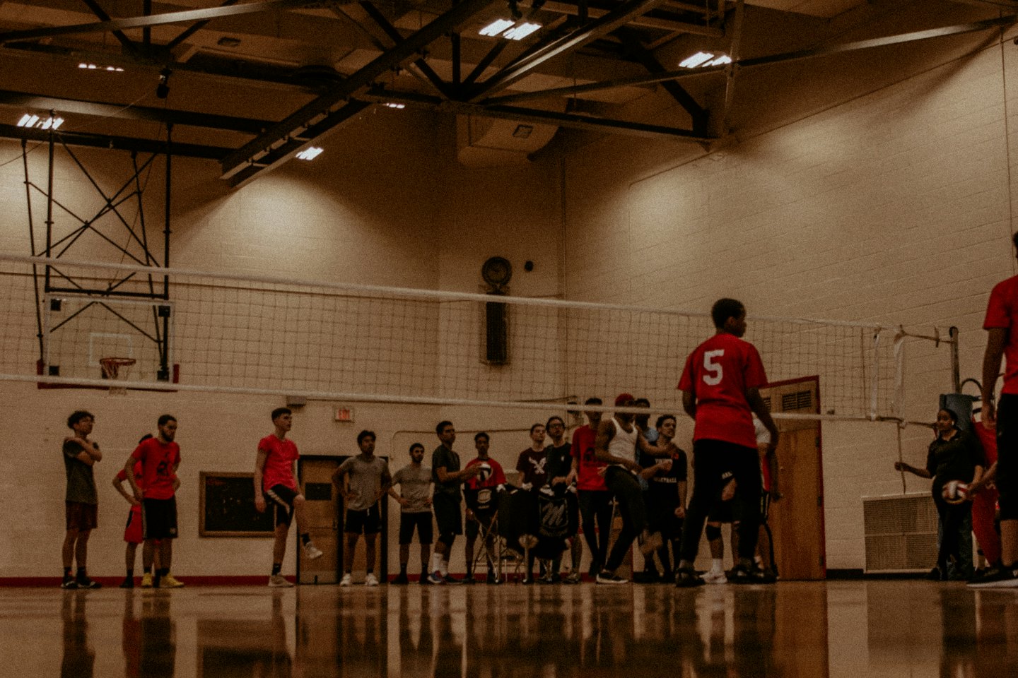 Junge Erwachsene spielen Volleyball in einer Turnhalle.